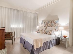 1 dormitorio con 1 cama blanca grande y piano en Padilla III en Madrid