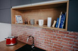 una cocina con una pared de ladrillo y un estante con libros en Little Home, en Liptovský Mikuláš