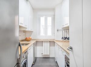 a white kitchen with white cabinets and a washer and dryer at Retiro VI in Madrid