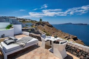 a balcony with a bed and a table and a view of the ocean at Epic View Suites in Akrotiri