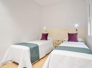 two beds in a room with white and purple at CASTELLO IV in Madrid