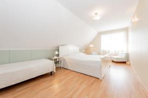 a white bedroom with two beds and a chair at Lubja Holiday House in Pärnu