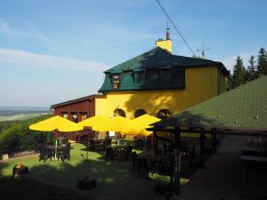 een gebouw met tafels en stoelen en gele parasols bij Penzion Vyhlídka Janovičky in Broumov