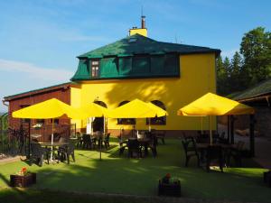 a building with tables and chairs with yellow umbrellas at Penzion Vyhlídka Janovičky in Broumov
