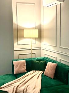 a green couch in a living room with a lamp at Velvet Home in Timişoara