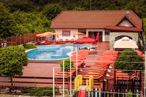 a pool with chairs and umbrellas next to a house at Pensiunea Iris in Turcineşti