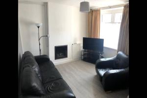 a living room with two leather couches and a television at Cosy end terrace in Lancaster