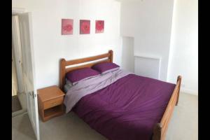 a bedroom with a bed with purple sheets and a nightstand at Cosy end terrace in Lancaster