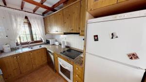 a kitchen with a white refrigerator and wooden cabinets at Casa Rozalejo - A Murcia Holiday Rentals Property in San Javier