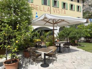 patio ze stołami, krzesłami i parasolem w obiekcie Albergo Bellavista w mieście Limone sul Garda