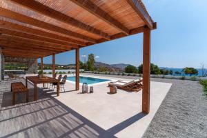 a patio with a wooden pergola and a swimming pool at Terra d'Oro Sea view villa with private pool in Kiotari