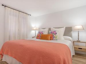 a white bedroom with a large bed with orange sheets and pillows at CHUECA V in Madrid