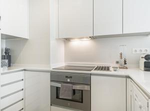 a kitchen with white cabinets and a stove top oven at ALONSO MARTINEZ II in Madrid