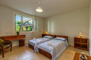 a bedroom with two beds and a desk and a window at Villa Berenice Au Bord Du Lac in Comabbio