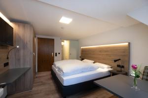 Schlafzimmer mit einem großen weißen Bett und einem Schreibtisch in der Unterkunft Gasthof Kreuz in Vöhrenbach