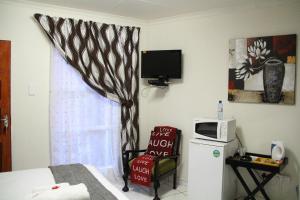 a bedroom with a bed and a microwave and a window at Memra Guest House in Ladysmith