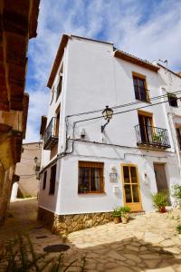 a white building with windows and a balcony at Casa El Cielo, in the heart of Old Town in Chulilla