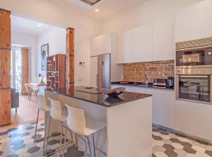 a kitchen with white cabinets and a bar with stools at Bailen Palacio Real in Madrid