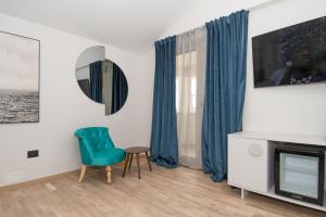 un soggiorno con sedia verde e TV di Fra&Kat Rooms a Premantura