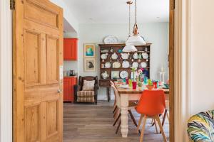 a dining room with a table and a kitchen with red cabinets at Aldeburgh Family House in Aldeburgh