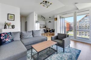 a living room with a couch and a table and chairs at GRANO FLATS Gdańsk - RiverFront Apartment in Gdańsk