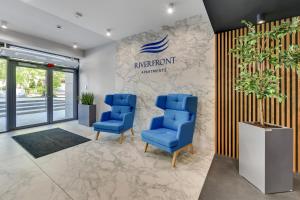 an office with two blue chairs in front of a sign at GRANO FLATS Gdańsk - RiverFront Apartment in Gdańsk