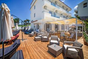 una terraza de madera con sillas, mesas y sombrillas en San Georgio Boutique Hotel by Hotelius, en Agios Georgios Pagon