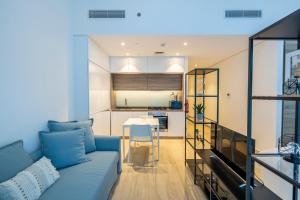 a living room with a blue couch and a kitchen at Cozy Yet Stylish Unit Studio One Marina in Dubai