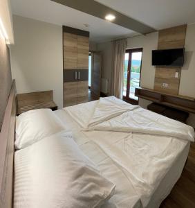 a large white bed in a room with a television at Hotel Roškar in Ptuj