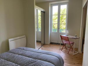 a bedroom with a bed and a table and a chair at AU COEUR DES SOURCES - Face aux Parcs & Thermes - Hypercentre in Vichy