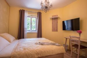 a bedroom with a bed and a desk and a television at Vila Radolca apartments and rooms in Radovljica