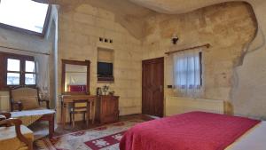 a bedroom with a bed and a desk in a room at Vezir Cave Suites in Goreme