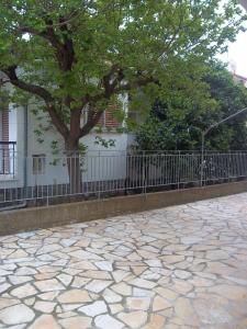 a tree and a fence next to a sidewalk at Poulithra Beach in Poulithra