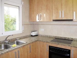 kuchnia z drewnianymi szafkami, umywalką i oknem w obiekcie Holiday Home Bretos 8 - CGE 215 by Interhome w mieście Fonts