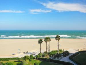 uma vista para uma praia com palmeiras e para o oceano em Apartment Grand Sud-2 by Interhome em Canet-en-Roussillon