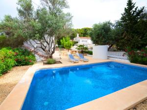 a swimming pool in a yard with chairs and trees at Holiday Home La Cigarra by Interhome in Calpe