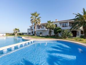 a swimming pool in front of a house with palm trees at Apartment Nueva Playa-1 by Interhome in Les Deveses	