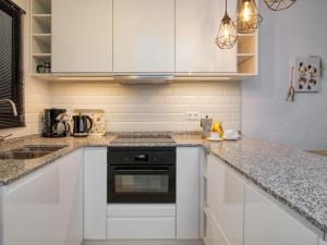 a kitchen with white cabinets and a stove top oven at Apartment Nueva Playa-1 by Interhome in Les Deveses	