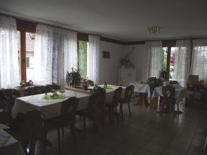 ein Esszimmer mit Tischen, Stühlen und Fenstern in der Unterkunft Gästehaus Bettina in Sipplingen