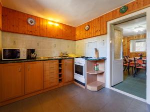 a kitchen with wooden cabinets and a dining room with a table at Holiday Home Amaryllis by Interhome in Balatonakarattya