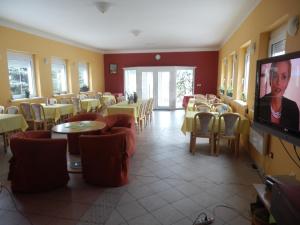 a restaurant with tables and chairs and a flat screen tv at Penzion Richnava in Štiavnické Bane