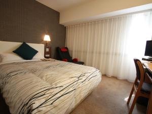 1 dormitorio con cama, escritorio y ventana en Kanazawa Manten Hotel Ekimae, en Kanazawa