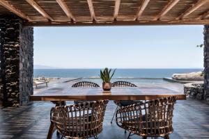 a wooden table and chairs on a patio with the ocean at Colombos Beachfront in Foinikiá