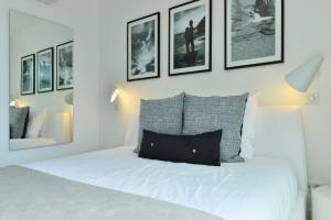 a bedroom with a white bed with pictures on the wall at Rêve de Saint Barth - Vue Mer - Piscine Chauffée & Jacuzzi in Gustavia