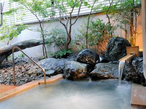 a pool of water with rocks and a waterfall at Kanazawa Manten Hotel Ekimae in Kanazawa