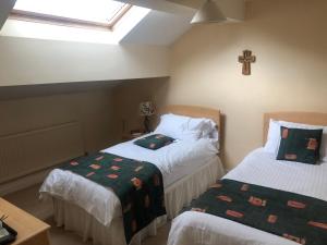 a bedroom with two beds and a cross on the wall at Whalley Abbey - Christian Retreat House offering B&B in Whalley