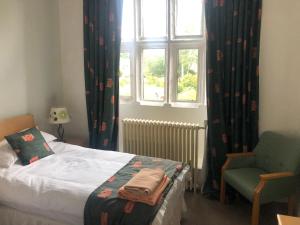 a bedroom with a bed and a chair and a window at Whalley Abbey - Christian Retreat House offering B&B in Whalley