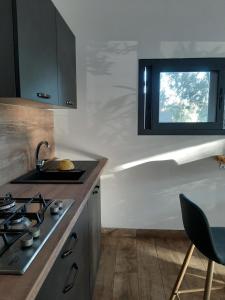 eine Küche mit einem Herd, einem Waschbecken und einem Fenster in der Unterkunft Mini Villa Giuseppina in Bonifacio