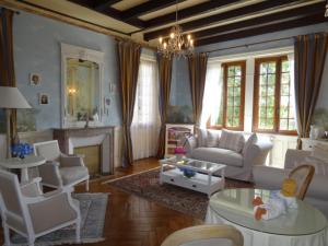 Elle comprend un salon doté d'un mobilier blanc et d'une cheminée. dans l'établissement Le Château de Vernières, à Talizat