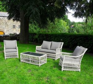 four wicker chairs and a coffee table in a yard at Le Château de Vernières in Talizat +5 photos
